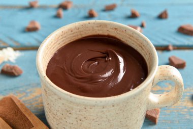 Mavi ahşap arka planda bir fincan lezzetli erimiş çikolata.