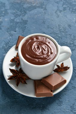 Mavi arka planda lezzetli erimiş çikolatalı bir fincan.