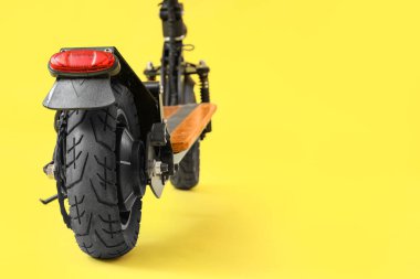 Sarı arka planda modern elektrikli scooter.