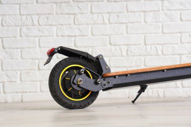 Modern elektrikli scooter beyaz tuğla duvarın yanında, yakın plan.