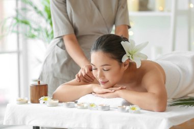 Çiçekli genç Asyalı kadın spa salonunda masaj yaptırıyor.