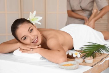 Çiçekli genç Asyalı kadın spa salonunda masaj yaptırıyor.
