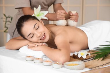 Çiçekli genç Asyalı kadın spa salonunda masaj yaptırıyor.