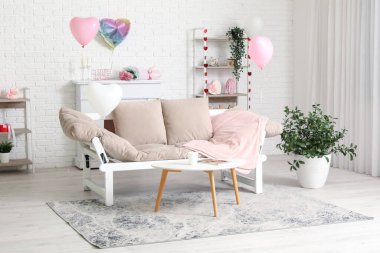 Sevgililer Günü kutlamaları için rahat kanepesi ve süslemeleri olan modern oturma odasının içinde.