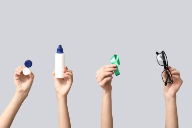 Kontakt lensler için konteynırı olan kadın eller, solüsyon şişesi, yeşil kurdele ve gri arka planda gözlük. Glaucoma farkındalık kavramı