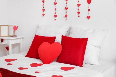 Kalp şeklinde yastıklı ve kağıt kalpli rahat bir yatak. Sevgililer Günü kutlaması