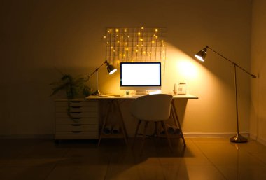 Ofis içi işyeri, boş bilgisayar ve geceleri parlayan lambalar.