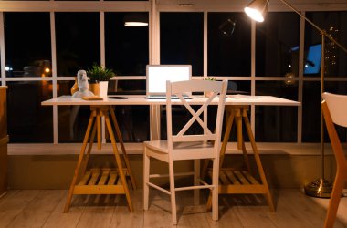 Geceleri ofisteki pencerenin yanında dizüstü bilgisayarı olan işyeri