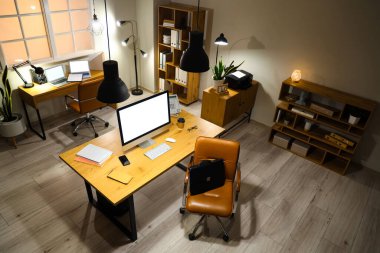 Masaları ve parlak lambaları olan modern ofisin içinde.