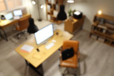 Masaları ve parlayan lambaları olan modern ofisin bulanık görüntüsü