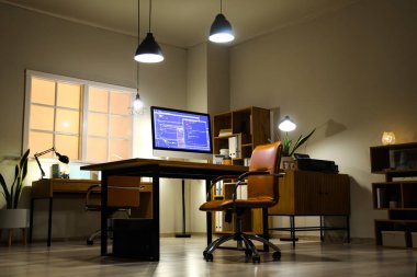 Masaları ve parlak lambaları olan modern ofisin içinde.