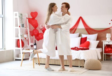 Young couple hugging in bedroom on Valentine's Day