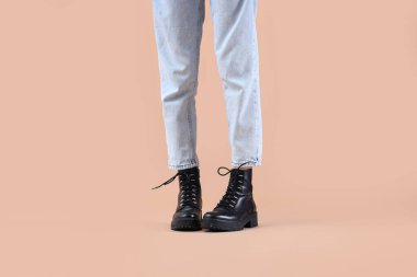 Bej arka planda siyah çizme giyen kadın bacaklar.