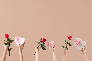 Kalp şeklinde balonlar tutan kadın eller ve bej arka planda güzel güller. Sevgililer Günü kutlaması