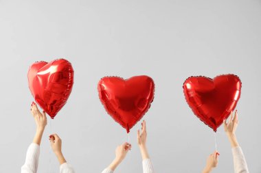 Beyaz arka planda kalp şeklinde balonlar tutan kadın eller. Sevgililer Günü kutlaması