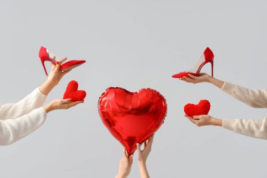 Kalpleri tutan kadın eller ve beyaz arka planda kırmızı topuklu ayakkabılar. Sevgililer Günü kutlaması