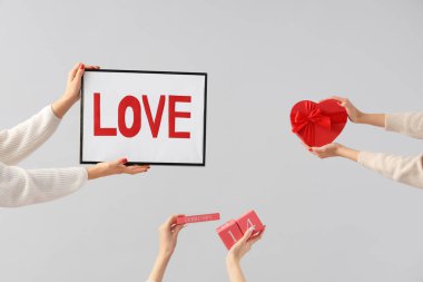 Sevgi, küp takvimi ve beyaz arka planda kalp şeklinde hediye kutusu olan çerçeveyi tutan kadın elleri. Sevgililer Günü kutlaması