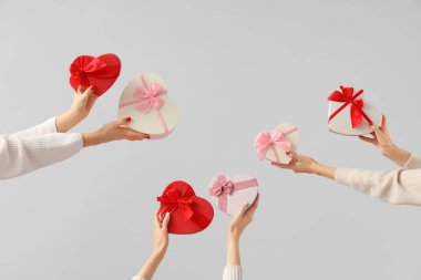 Beyaz arka planda kalp şeklinde farklı hediye kutuları tutan kadın elleri. Sevgililer Günü kutlaması