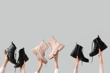 Gri arka planda çizmeleri tutan kadın eller