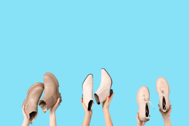 Mavi arka planda farklı ayakkabılar tutan kadın eller.