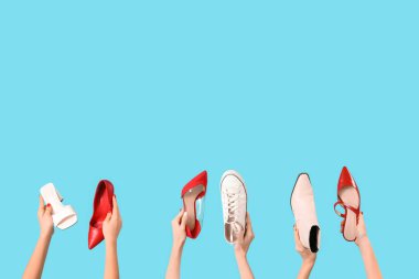 Mavi arka planda farklı ayakkabılar tutan kadın eller.