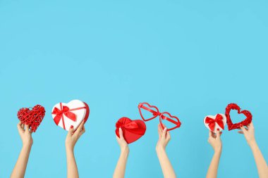 Kalp şeklinde hediye kutuları, mavi arka planda gözlük ve kalpler tutan kadın elleri. Sevgililer Günü kutlaması