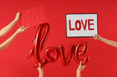 Kadın el yazısı, çerçeve ve balonlar. Kırmızı arka planda aşk kelimesi var. Sevgililer Günü kutlaması