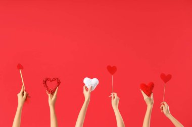 Kalpleri tutan kadın eller ve kırmızı arka planda Aşk Tanrısı 'nın oku. Sevgililer Günü kutlaması