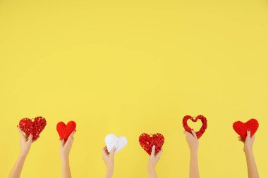 Sarı arka planda farklı kalpleri tutan kadın elleri. Sevgililer Günü kutlaması