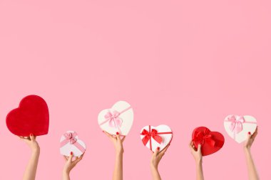 Pembe arka planda kalp şeklinde farklı balonlar tutan kadın elleri. Sevgililer Günü kutlaması