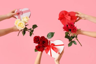 Pembe arka planda güllü kalp şeklinde balonlar tutan kadın elleri. Sevgililer Günü kutlaması