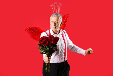 Aşk tanrısı gibi giyinmiş, kırmızı arka planda güller olan olgun bir adam. Sevgililer Günü kutlaması