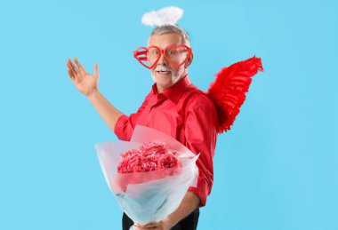 Aşk tanrısı gibi giyinmiş, mavi arka planda güller olan olgun bir adam. Sevgililer Günü kutlaması