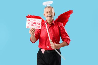 Aşk tanrısı gibi giyinmiş, elinde ruj izi ve mavi arka planda fiyonk olan bir kağıt tutan olgun bir adam. Sevgililer Günü kutlaması