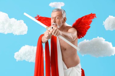 Aşk tanrısı gibi giyinmiş olgun bir adam mavi arka planda bulutlara ok atıyor. Sevgililer Günü kutlaması