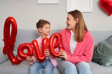 Balonlardan yapılmış kelime sevgisiyle küçük bir çocuk ve Sevgililer Günü 'nde annesi evde oturuyor.