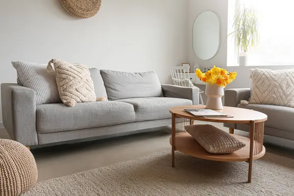 Kahve masasının üzerinde rahat kanepeler ve vazo olan modern oturma odasının içinde.
