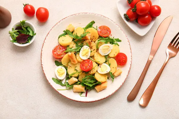 Composition with tasty potato salad with eggs and tomatoes on light background
