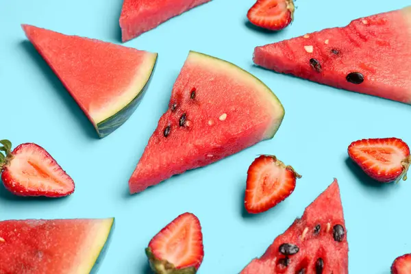 Taze karpuz parçaları ve mavi arka planda çilekler.