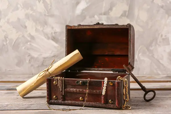 Hazineli eski sandık, anahtar ve harita açık ahşap masa üzerinde grunge duvarın yanında.