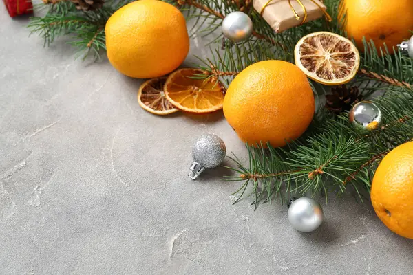 Köknar dallı lezzetli portakallar ve gri arka planda Noel topları