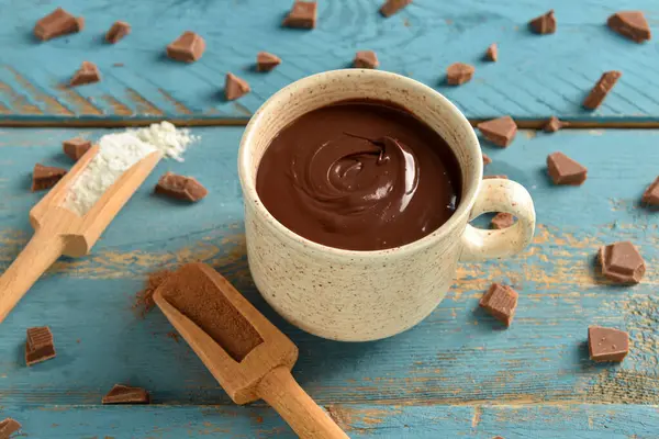 Mavi ahşap arka planda bir fincan lezzetli erimiş çikolata.