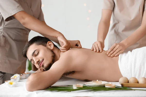 Young man getting massage from therapists in spa salon