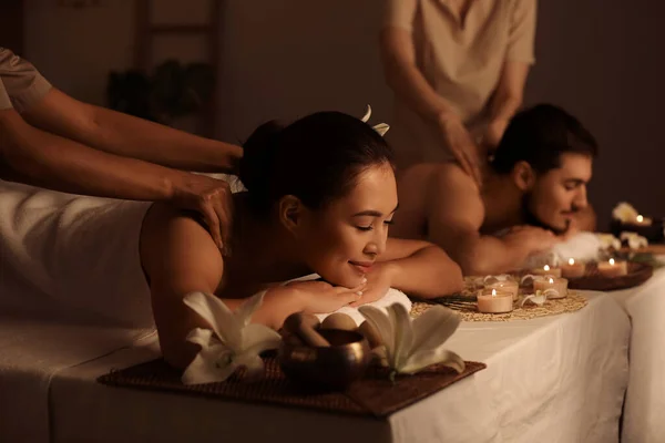 Young couple getting massage in dark spa salon