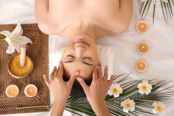 Genç Asyalı kadın spa salonunda baş masajı yaptırıyor.