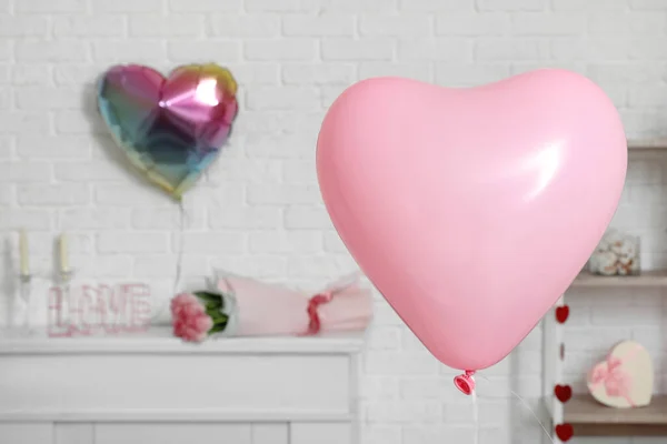 Pink heart-shaped balloon in festive living room, closeup. Valentine\'s Day celebration
