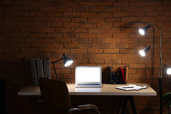 Karanlık ofis, iş yeri, boş laptop ve geceleri parlayan lambalar.