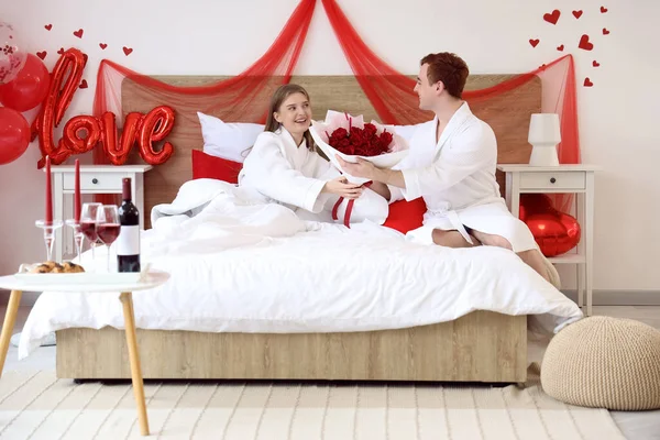 Sevgililer Günü 'nde yatak odasında erkek arkadaşından gül alan genç bir kadın.