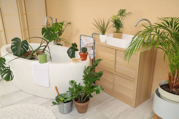 Banyonun içinde yeşil bitkiler ve lavabo var.