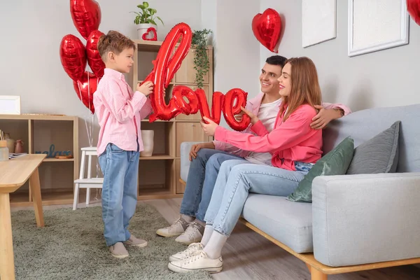 Little boy with his parents and word LOVE made of balloons at home on Valentine\'s Day